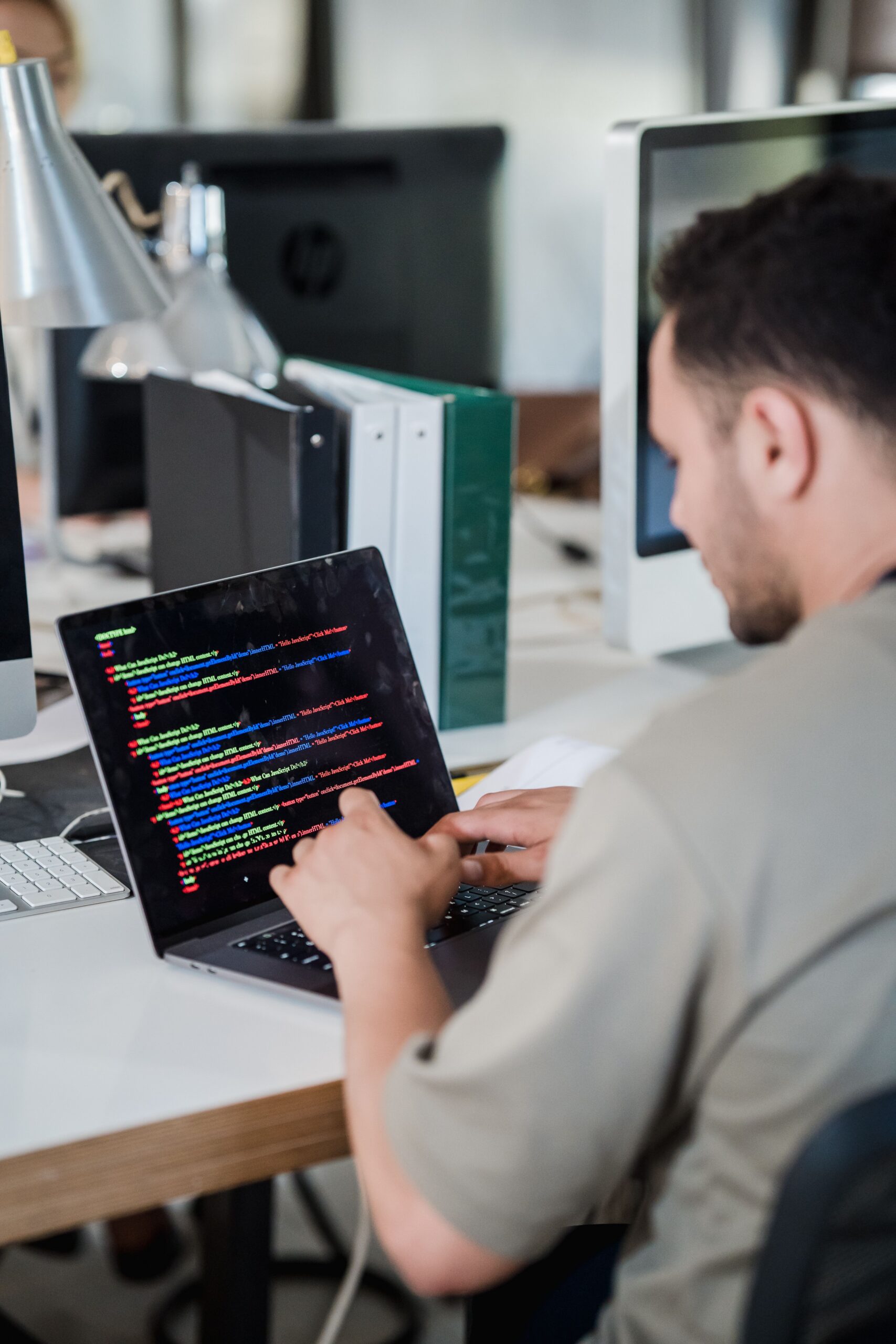 Software developer writing code on a laptop in a modern office