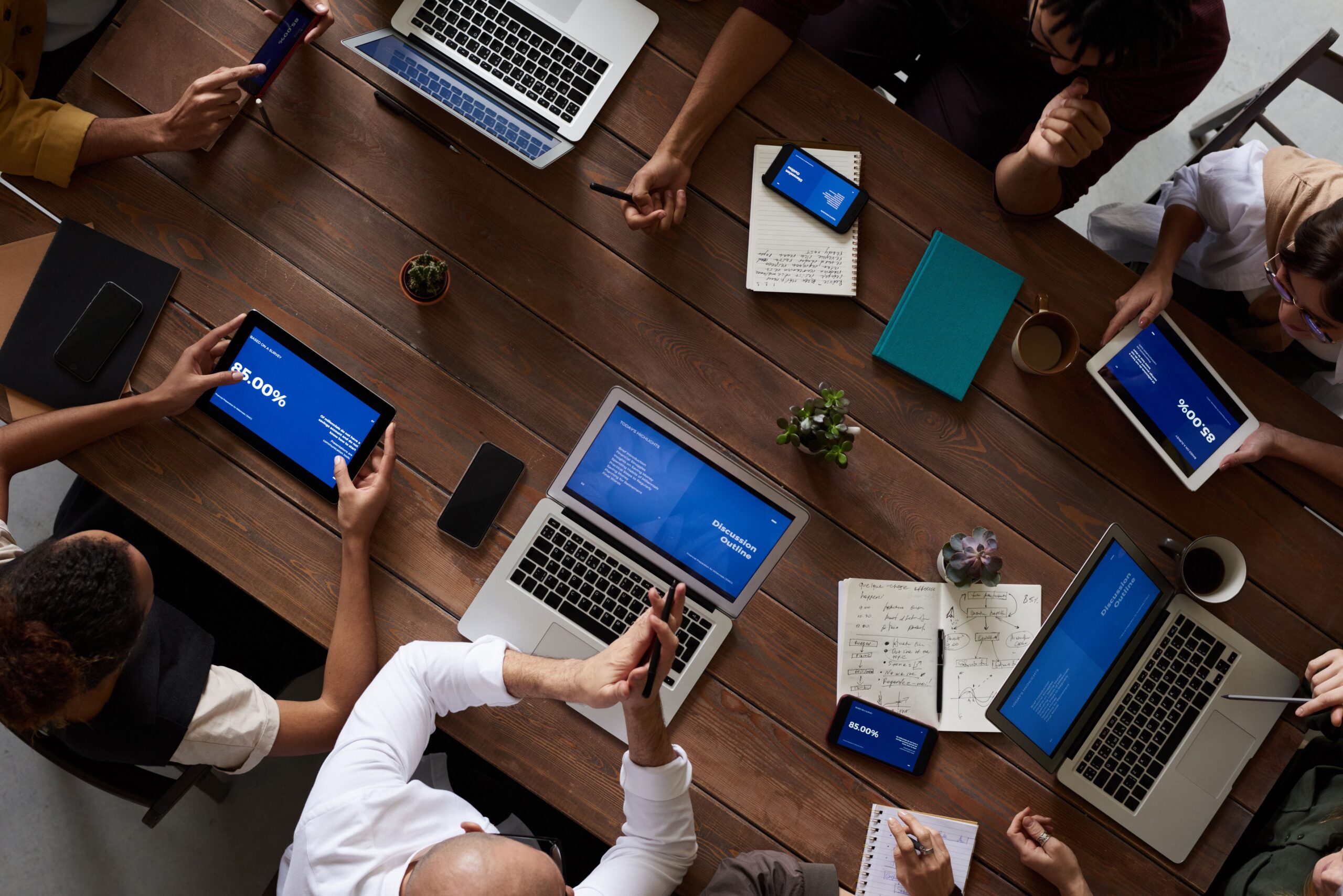 Overhead view of a small team around a table with laptops and notes planning a project
